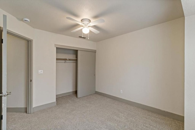 unfurnished bedroom featuring ceiling fan, light colored carpet, and a closet