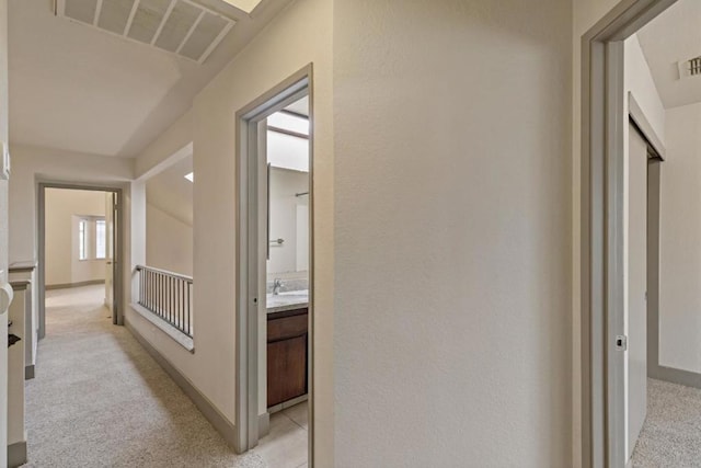 corridor with sink, vaulted ceiling, and light carpet