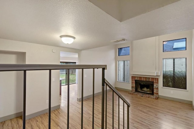 hall with light hardwood / wood-style floors and a textured ceiling