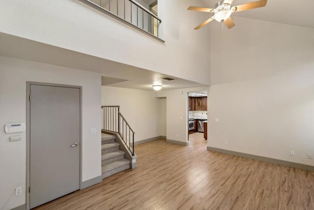 interior space with a towering ceiling, ceiling fan, and light hardwood / wood-style floors