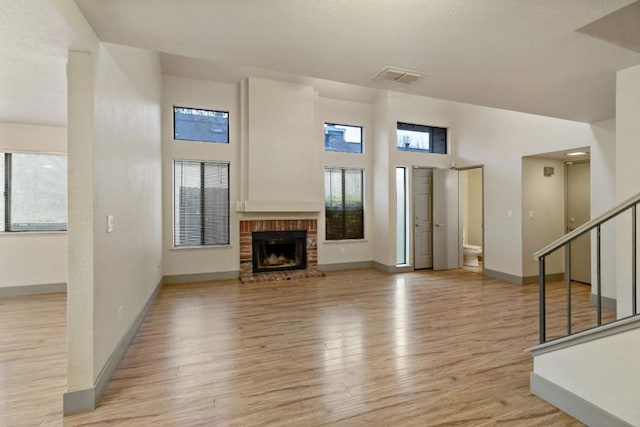 unfurnished living room with a brick fireplace, a wealth of natural light, and light hardwood / wood-style flooring