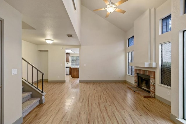 unfurnished living room featuring a brick fireplace, light wood-type flooring, and ceiling fan