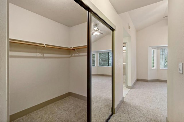 walk in closet with lofted ceiling, light colored carpet, and ceiling fan