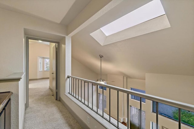 hallway featuring light colored carpet and vaulted ceiling with skylight