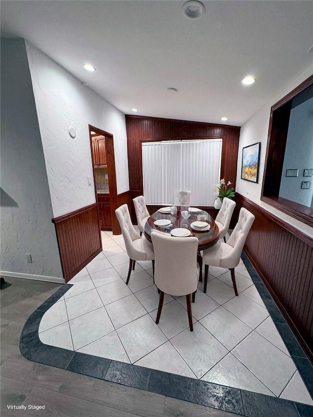 dining area with wood walls and light tile patterned flooring