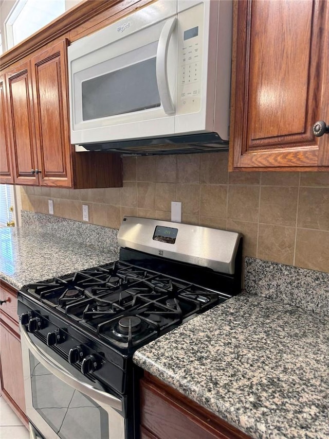 kitchen with dark stone countertops, gas stove, and tasteful backsplash