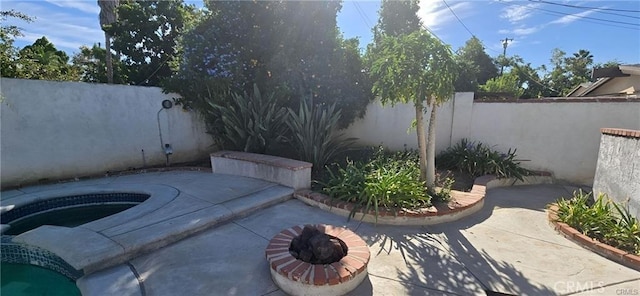 view of patio featuring a fire pit and an outdoor hot tub