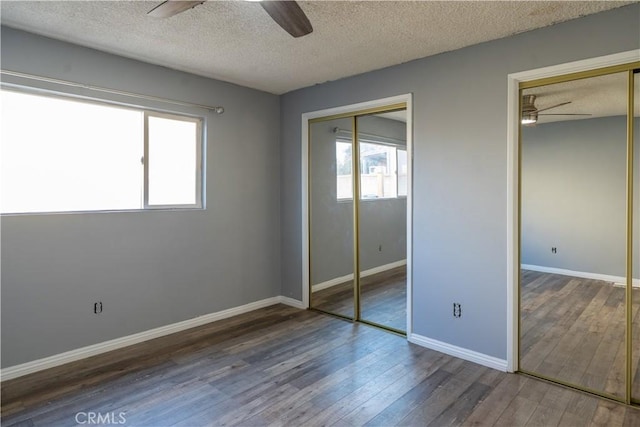 unfurnished bedroom with a textured ceiling, ceiling fan, and dark wood-type flooring