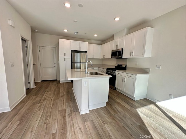 kitchen featuring white cabinetry, a center island with sink, appliances with stainless steel finishes, light wood-type flooring, and sink