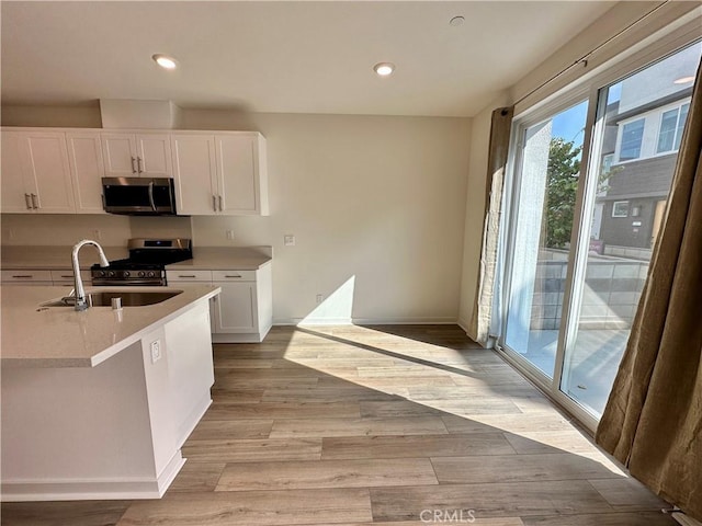 kitchen featuring light hardwood / wood-style floors, sink, stainless steel appliances, and white cabinetry