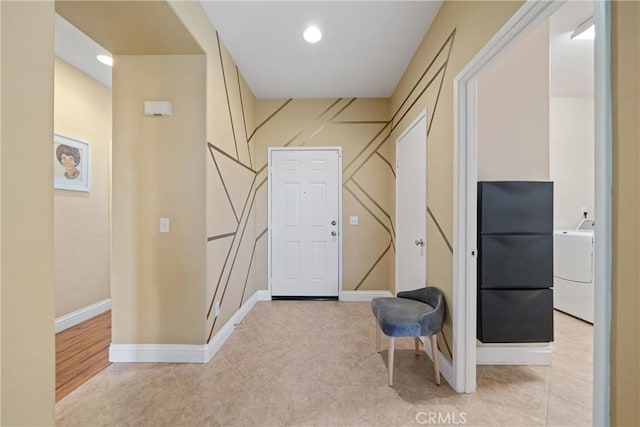 hall with washer / dryer and light tile patterned floors