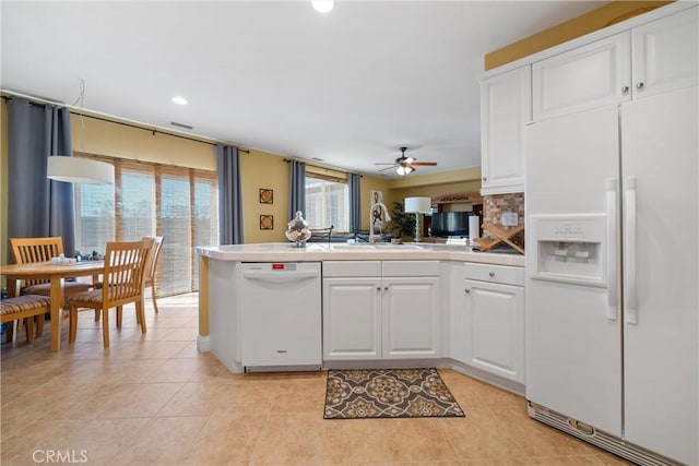 kitchen with white appliances, kitchen peninsula, ceiling fan, white cabinets, and sink