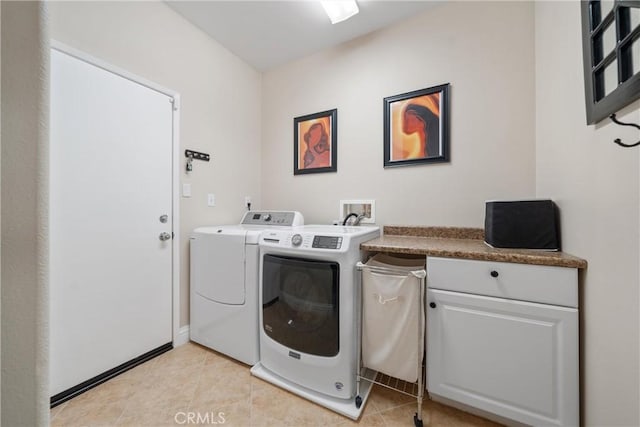 clothes washing area featuring cabinets, separate washer and dryer, and light tile patterned floors