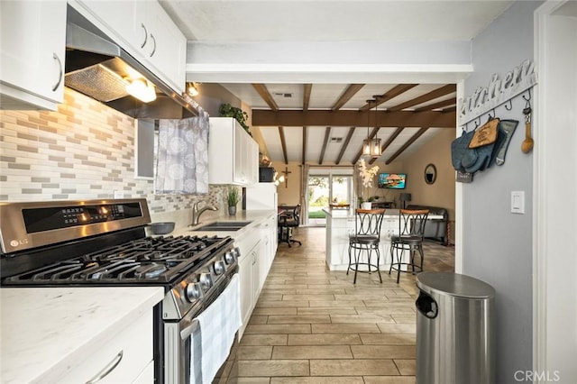 kitchen featuring exhaust hood, white cabinetry, sink, gas stove, and lofted ceiling with beams