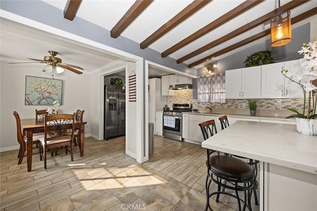 kitchen with hanging light fixtures, decorative backsplash, white cabinets, vaulted ceiling with beams, and stainless steel appliances