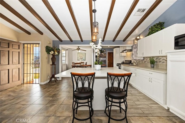 kitchen with a kitchen island, white cabinetry, vaulted ceiling with beams, and pendant lighting