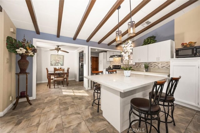 kitchen featuring decorative light fixtures, stainless steel range, white cabinetry, vaulted ceiling with beams, and backsplash