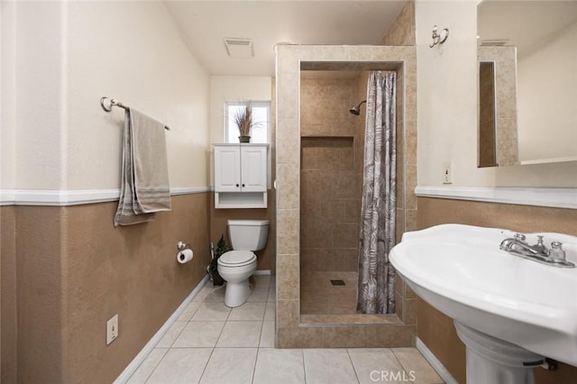 bathroom featuring tile patterned floors, toilet, walk in shower, and sink