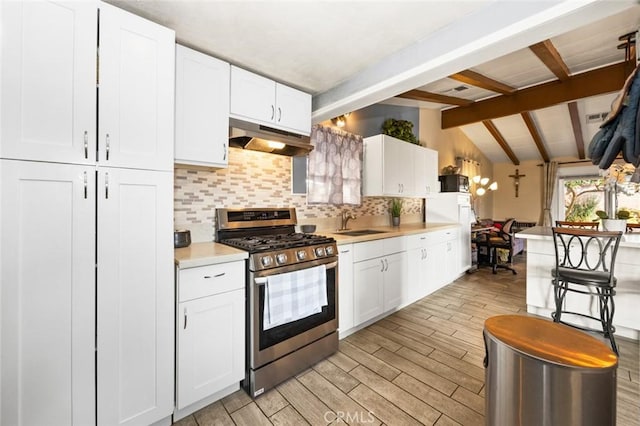 kitchen with sink, white cabinets, lofted ceiling with beams, light wood-type flooring, and stainless steel gas range