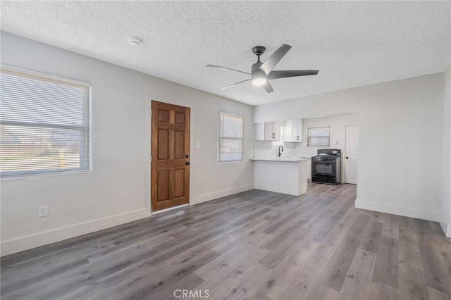 unfurnished living room with ceiling fan, a textured ceiling, sink, and hardwood / wood-style flooring