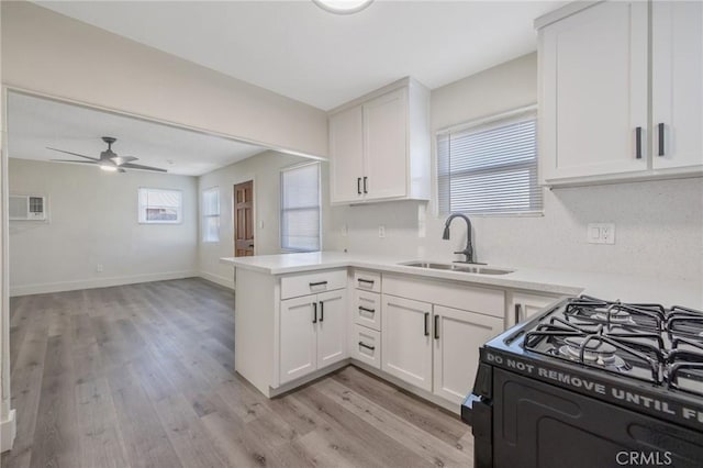 kitchen with kitchen peninsula, white cabinetry, gas stove, and sink