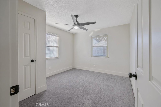 empty room with light carpet, a textured ceiling, ceiling fan, and a healthy amount of sunlight