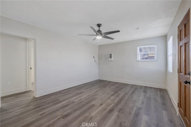 empty room with an AC wall unit, a textured ceiling, ceiling fan, and light hardwood / wood-style flooring