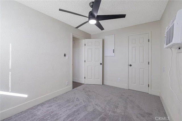 unfurnished bedroom with ceiling fan, a wall unit AC, carpet, and a textured ceiling