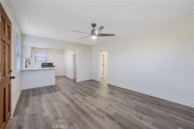 unfurnished living room featuring light hardwood / wood-style floors, ceiling fan, and a textured ceiling