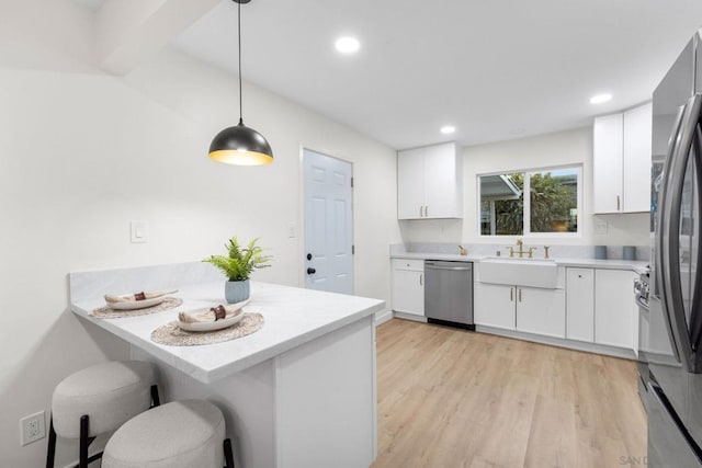 kitchen featuring white cabinetry, kitchen peninsula, hanging light fixtures, and stainless steel appliances