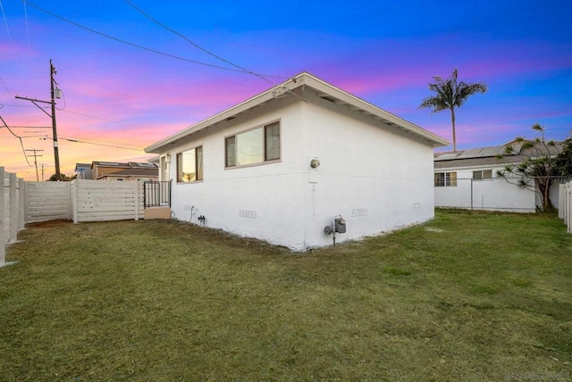 property exterior at dusk with a lawn