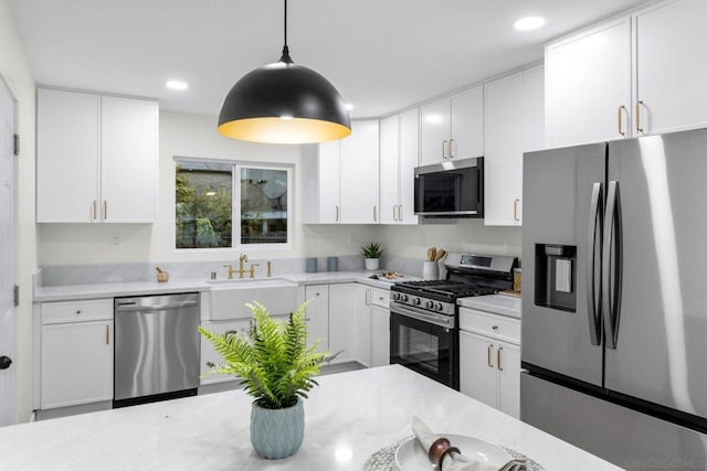 kitchen featuring stainless steel appliances, sink, white cabinetry, and decorative light fixtures