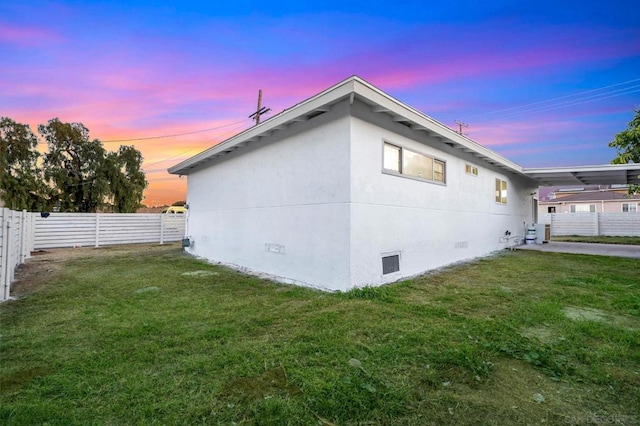 property exterior at dusk featuring central air condition unit and a yard