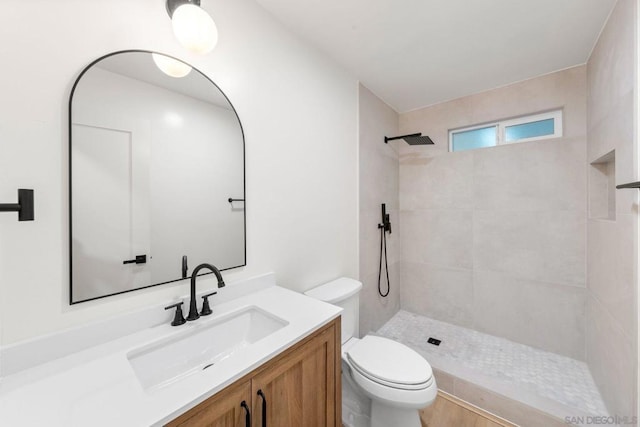 bathroom featuring toilet, vanity, and a tile shower