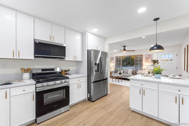 kitchen with white cabinets, appliances with stainless steel finishes, hanging light fixtures, light wood-type flooring, and ceiling fan