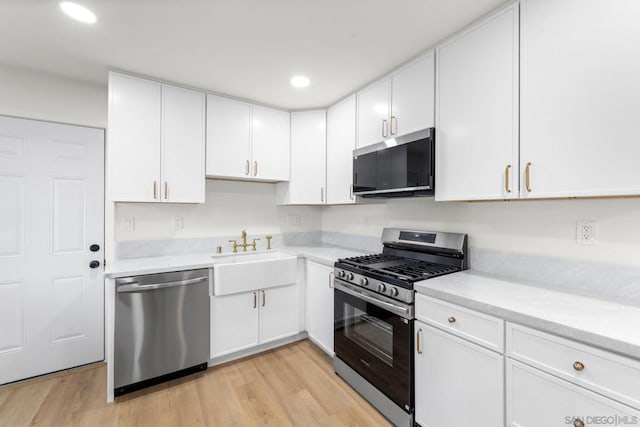 kitchen featuring light hardwood / wood-style floors, white cabinets, appliances with stainless steel finishes, and sink