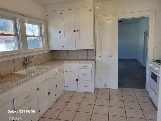 kitchen with sink, tile counters, tasteful backsplash, and white cabinetry