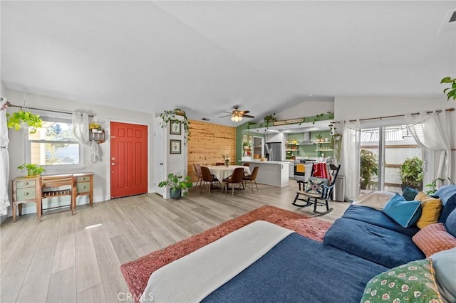 living room with lofted ceiling, hardwood / wood-style flooring, wood walls, and ceiling fan