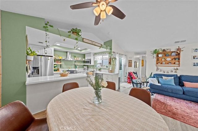 dining space featuring sink, light hardwood / wood-style floors, ceiling fan, and vaulted ceiling