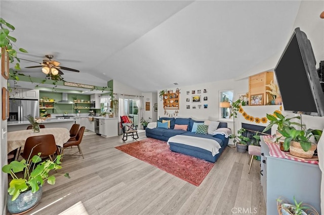 living room featuring ceiling fan, light wood-type flooring, and vaulted ceiling