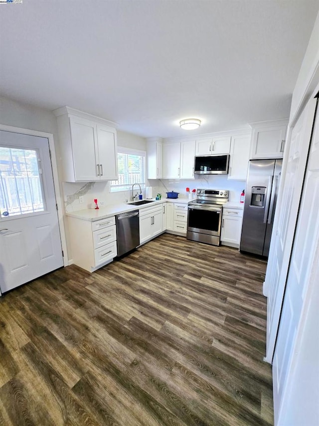 kitchen featuring appliances with stainless steel finishes, sink, dark hardwood / wood-style floors, white cabinets, and tasteful backsplash