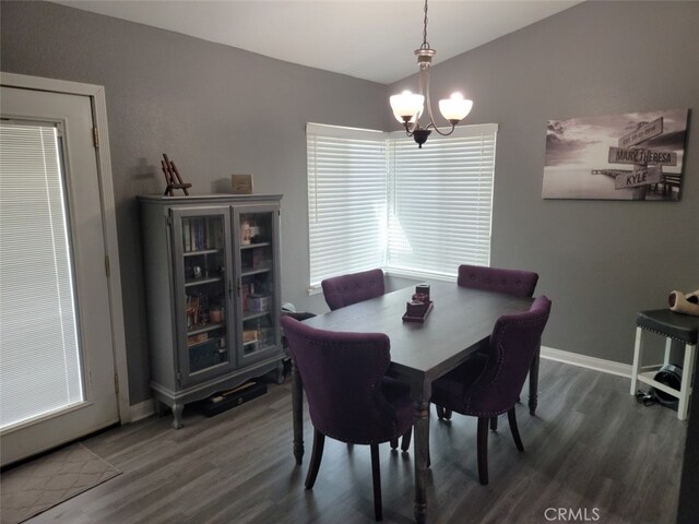 dining area with dark hardwood / wood-style flooring, a chandelier, and vaulted ceiling