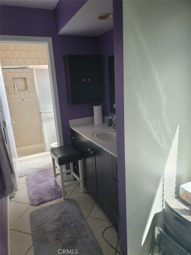 bathroom featuring tile patterned floors, tiled shower, and vanity