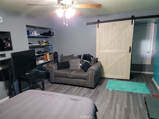 bedroom with ceiling fan, a barn door, and hardwood / wood-style floors