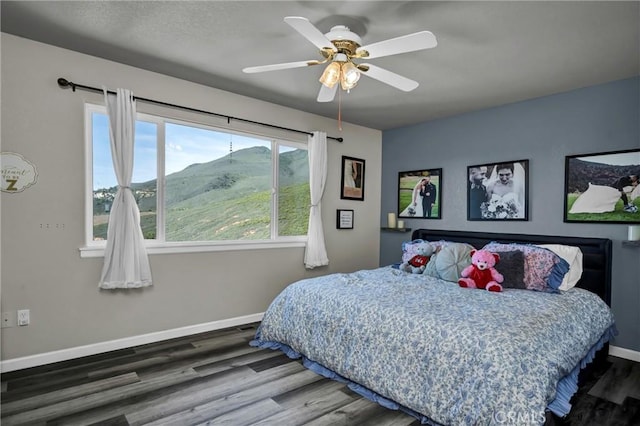 bedroom featuring wood-type flooring, a mountain view, and ceiling fan