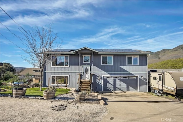 view of front of house featuring solar panels, a garage, and a mountain view