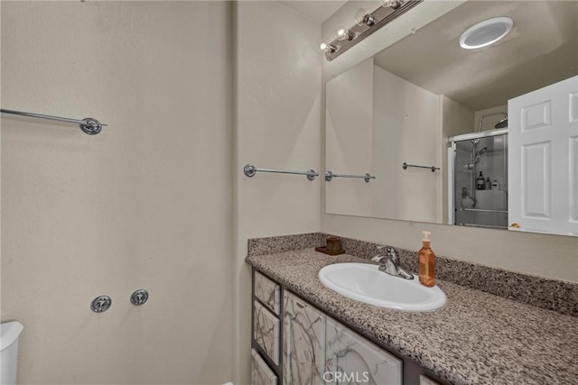 bathroom featuring vanity, a shower with door, and toilet