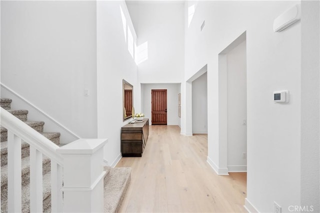 hall featuring light hardwood / wood-style floors and a towering ceiling