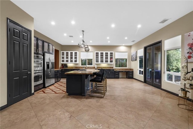 kitchen with light stone countertops, stainless steel appliances, a kitchen bar, and a kitchen island