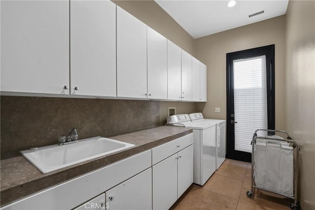 washroom with sink, cabinets, washing machine and dryer, and light tile patterned flooring